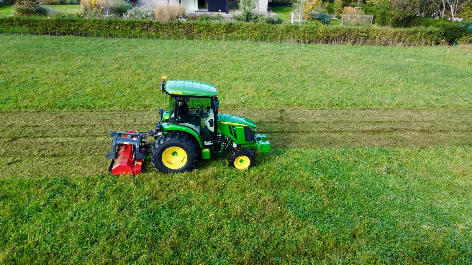 Tractor con desbrozadora de martillos segando hierba alta, visto desde arriba