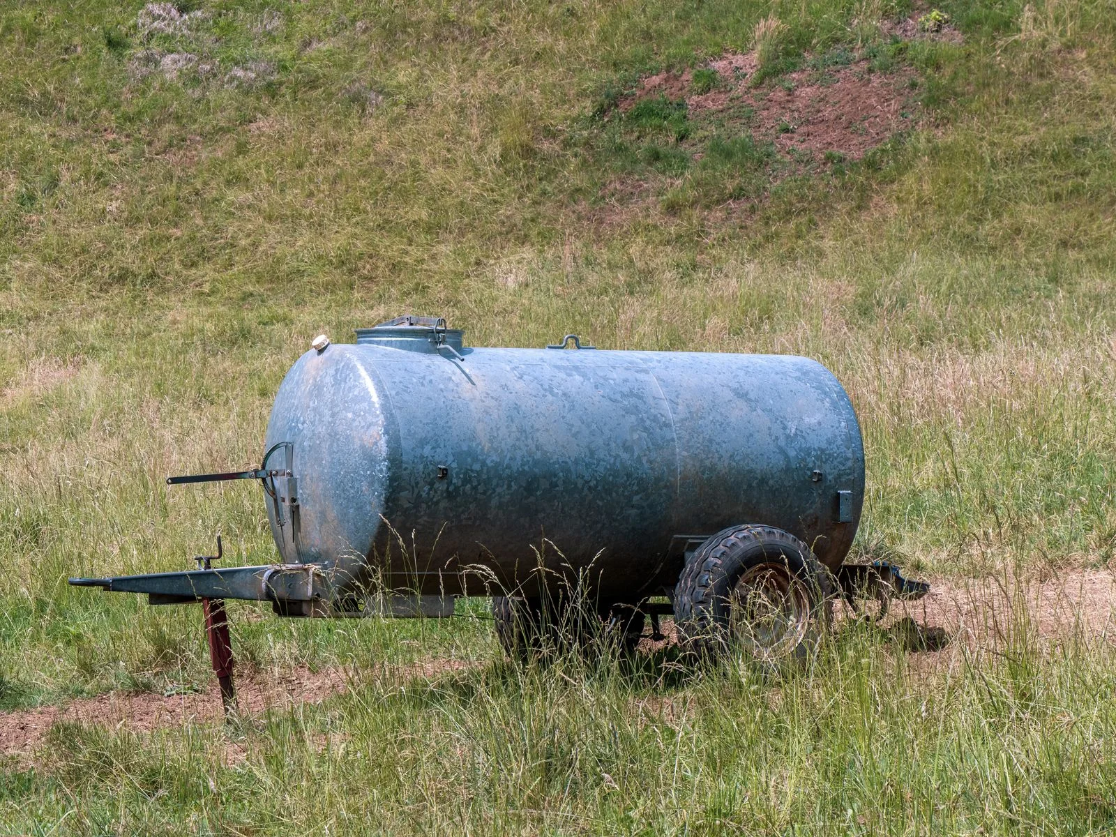 Cuba de agua galvanizada con ruedas preparada en el campo